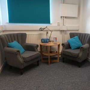 therapy room with two grey armchairs and a small table between them